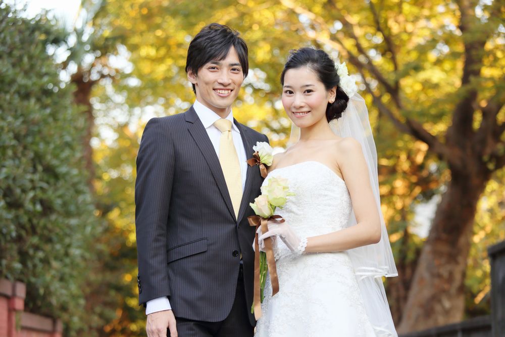 ブーケを掲げて笑顔で寄り添う、ウェディング姿の男女